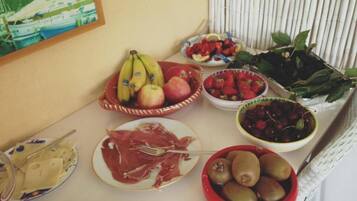 Una mesa con diversos alimentos, como frutas, quesos y embutidos.