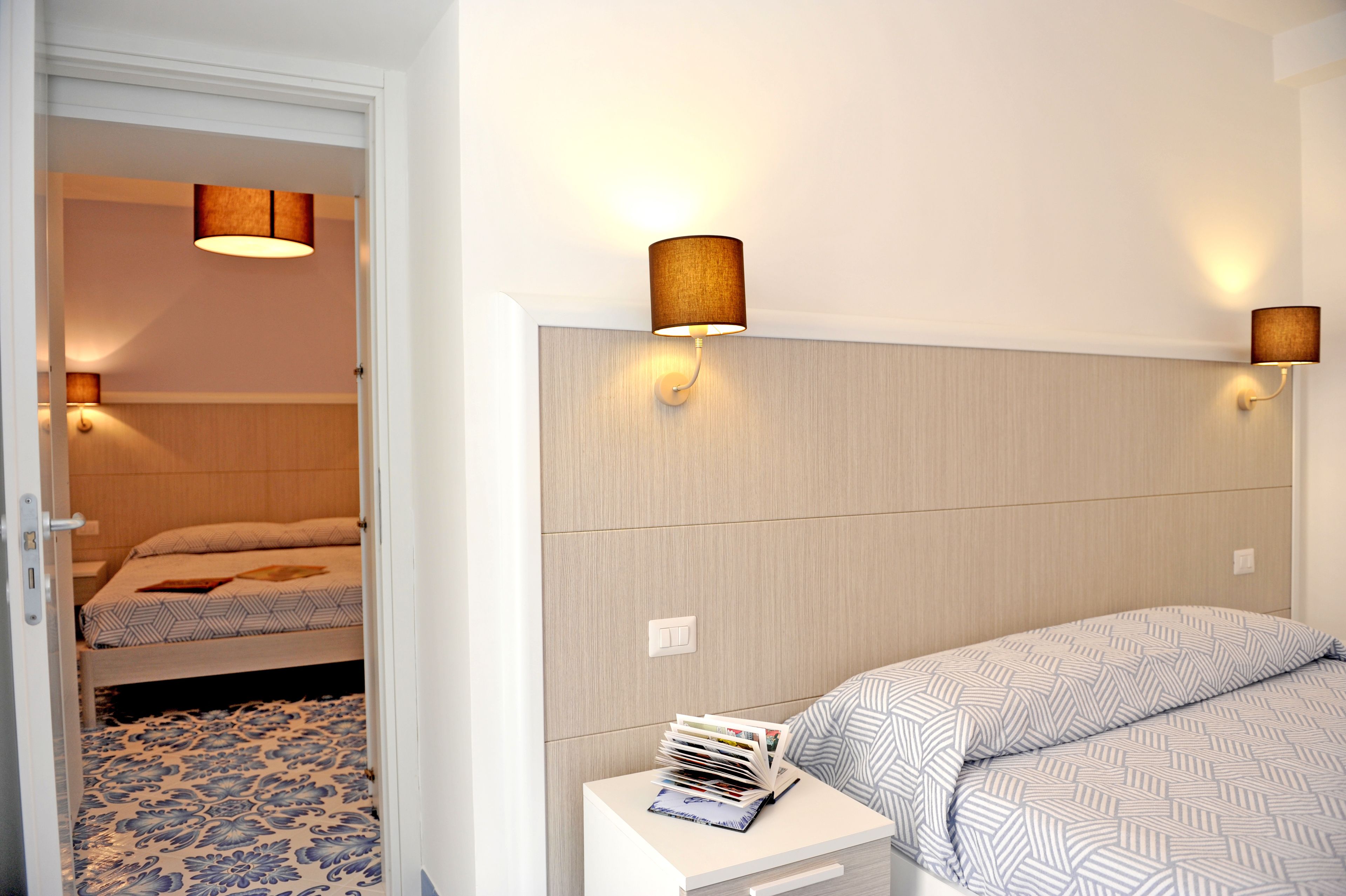 A bedroom with a bed, bedside table, and two wall-mounted lamps.