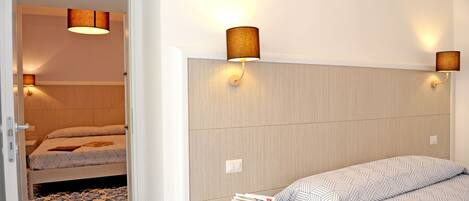A bedroom with a bed, bedside table, and two wall-mounted lamps.