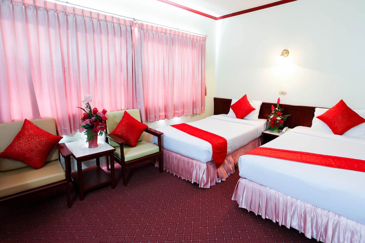 A hotel room with two beds, a sofa, a small table, and a nightstand.