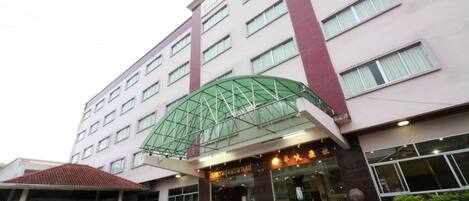 A multi-story hotel with a prominent green glass entrance canopy.