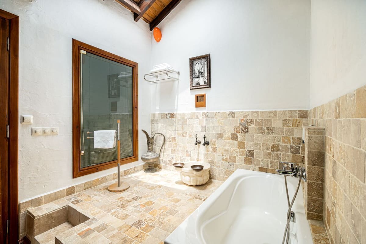 A bathroom with a bathtub, a sink, a toilet, and a window.