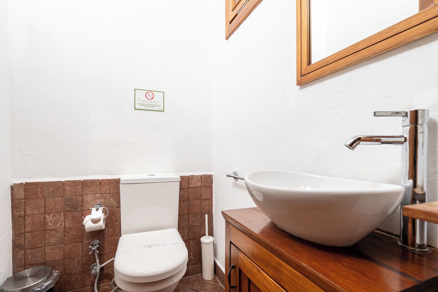 A compact bathroom with a white toilet, a vessel sink, and a wooden vanity.