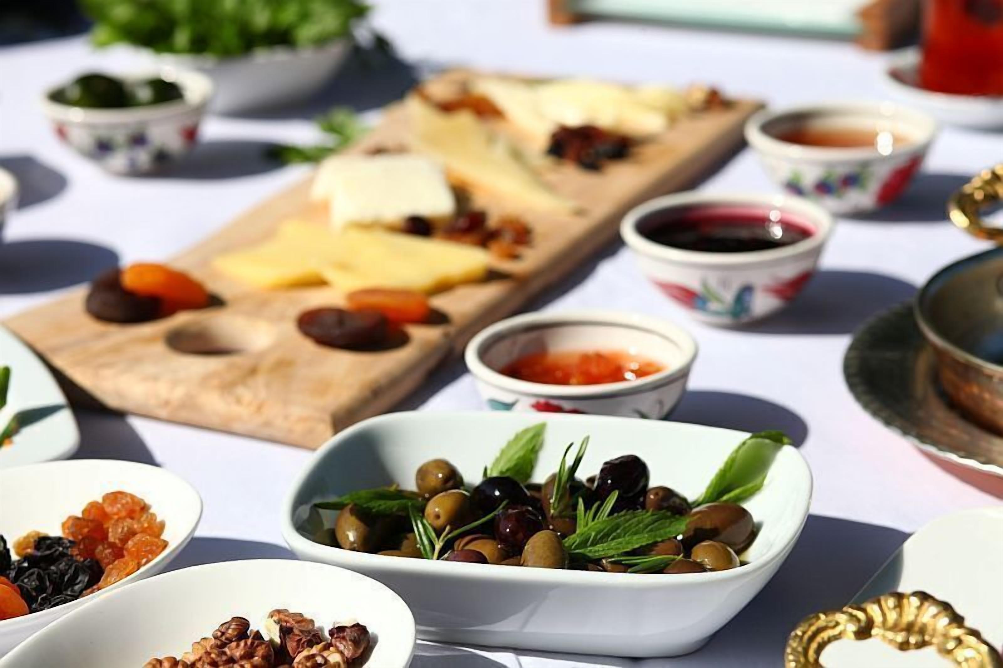A table with various food items including cheese, olives, and nuts, suggesting a buffet or communal dining setup.