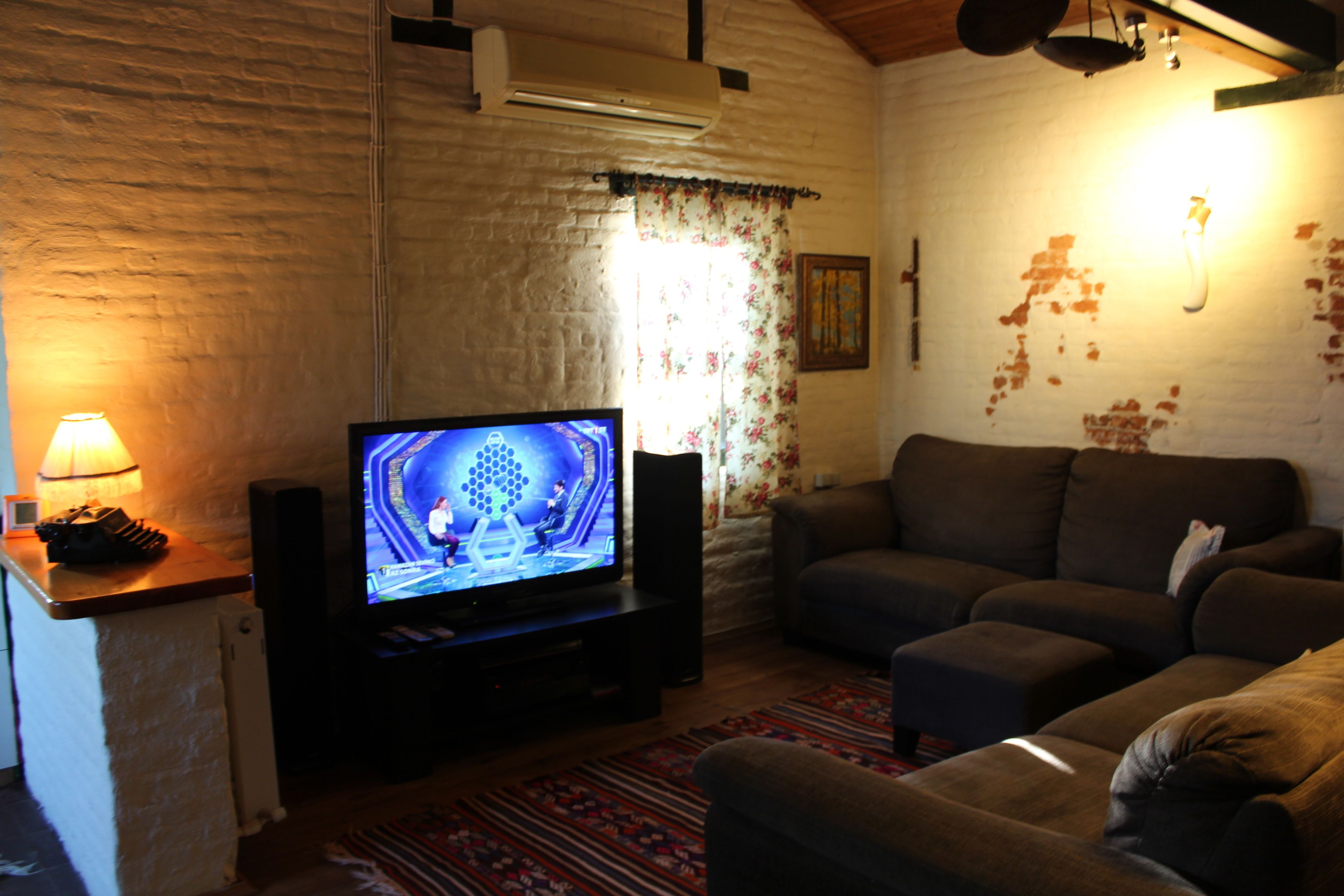 A living room with a television, a sofa, and a patterned rug.