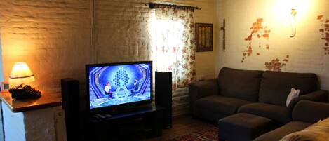 A living room with a television, a sofa, and a patterned rug.