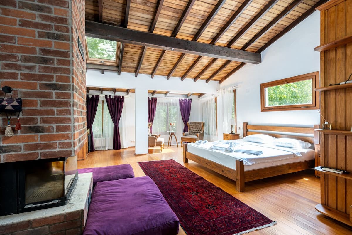 A bedroom with a wooden bed, a fireplace, and a large window.