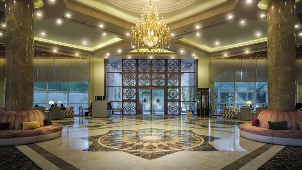 A spacious lobby with a large chandelier, marble flooring, and seating areas. - Grand Sultan Tea Resort & Golf (Kamalganj)