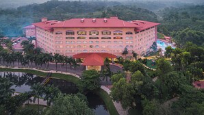A large, multi-story hotel with a red roof, surrounded by lush greenery and a pool area. - Grand Sultan Tea Resort & Golf (Kamalganj)