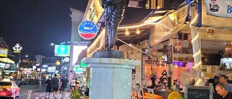 A statue on a pedestal outside a restaurant with a sign for 'Cafe UNO' and a menu board.