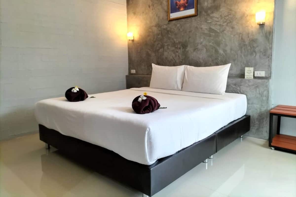A modern hotel room with a large bed, white linens, two pillows, and a decorative wall hanging.