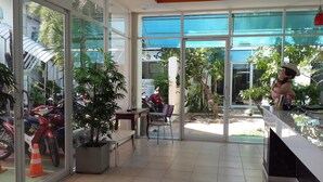 Un espacio interior amplio con ventanas grandes, plantas en macetas y una zona de estar.