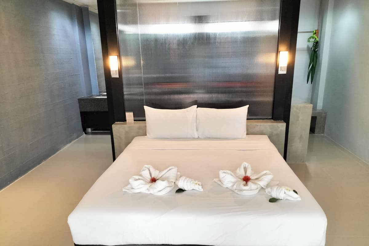 A modern hotel room with a large bed, white linens, and decorative towels.