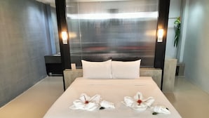 Una habitación de hotel moderna con una cama grande, ropa de cama blanca y toallas decorativas.