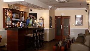 A bar area with stools, a sofa, and a television displaying news. - The W Hotel (Lagos)