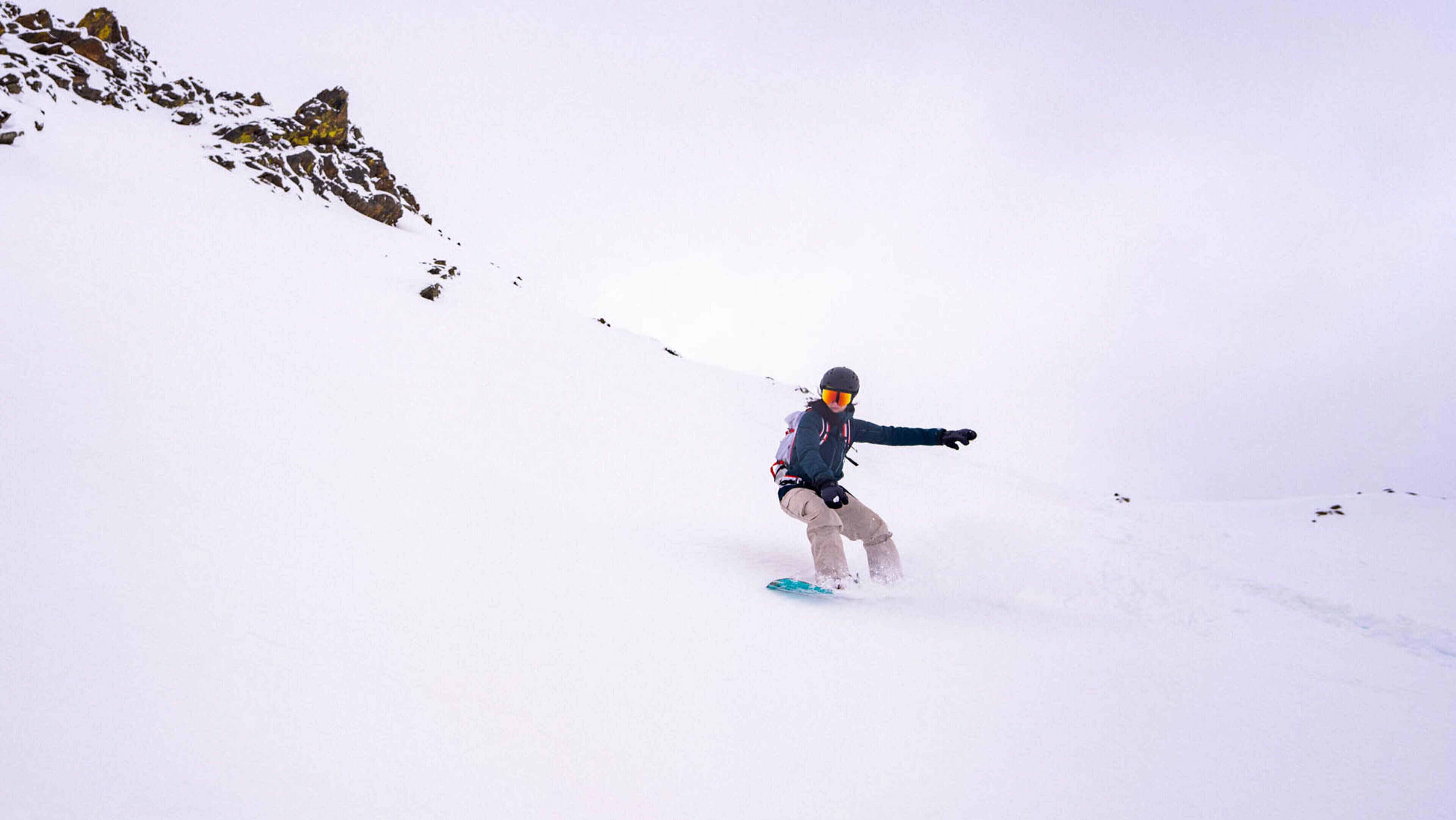 Una persona practica snowboard por una pendiente nevada.