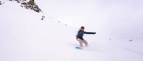 Una persona practica snowboard por una pendiente nevada.