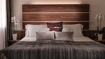 A neatly made bed with a patterned bedspread, a wooden headboard, and two nightstands with potted plants.