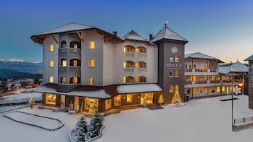 A multi-story hotel with balconies, a snow-covered courtyard, and illuminated windows.