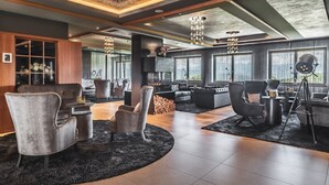 Un salon moderne doté d’une cheminée, de sièges confortables et de grandes fenêtres.
