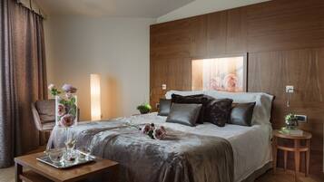 A well-appointed hotel room with a large bed, a wooden headboard, a bedside table with a lamp, and a small side table with a plant.