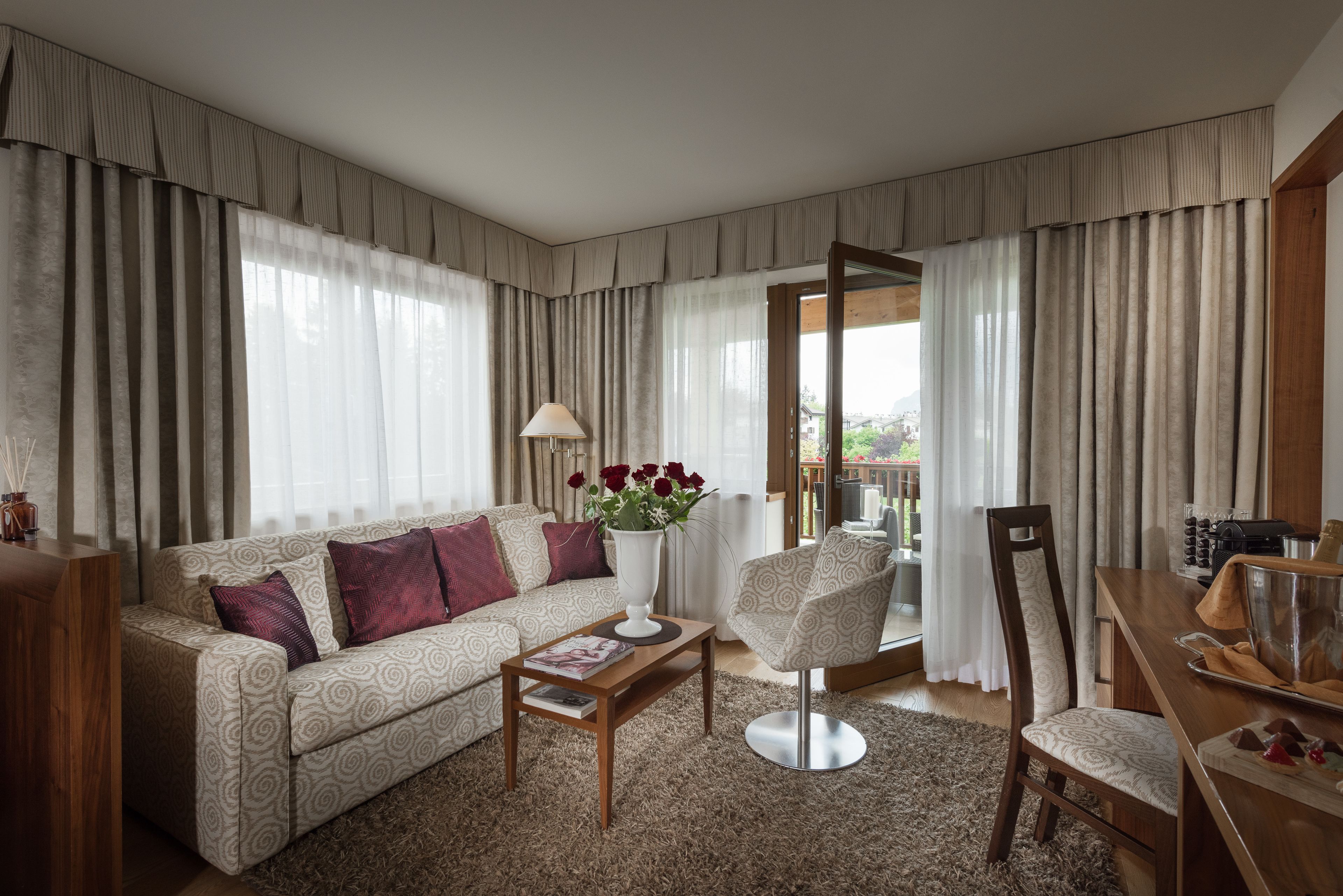 Ein stilvolles Wohnzimmer mit Sofa, Sessel, Couchtisch und Blumen in einer Vase.
