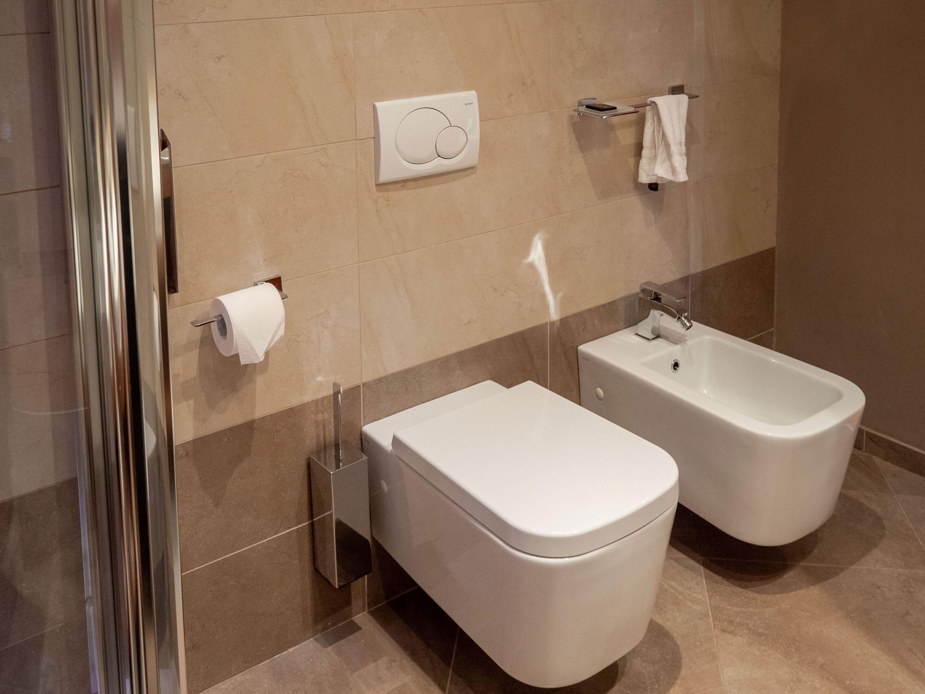 A modern bathroom with a toilet, bidet, and a towel rack.