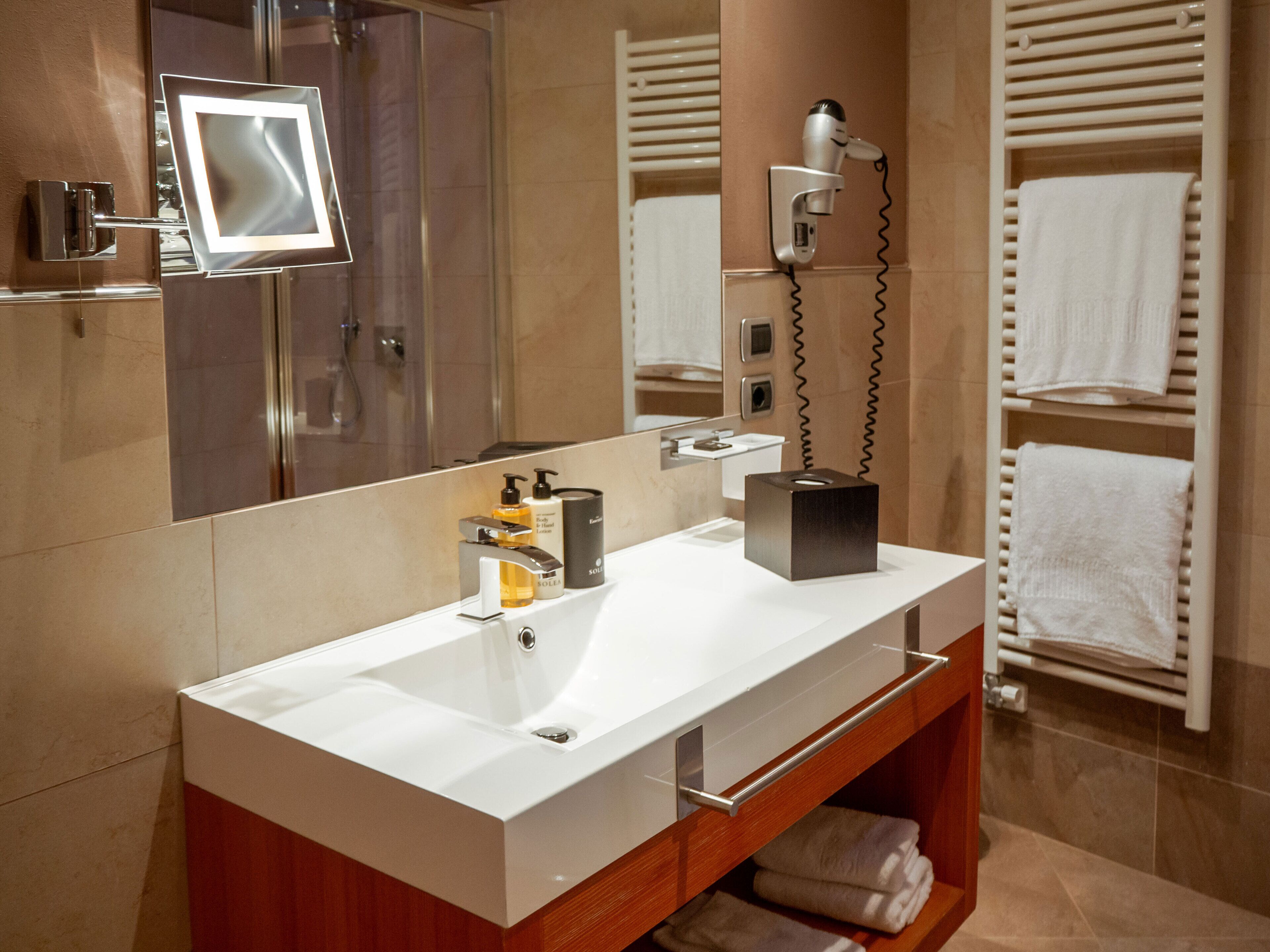 A modern bathroom with a double sink, a mirror, a hairdryer, and a towel rack.