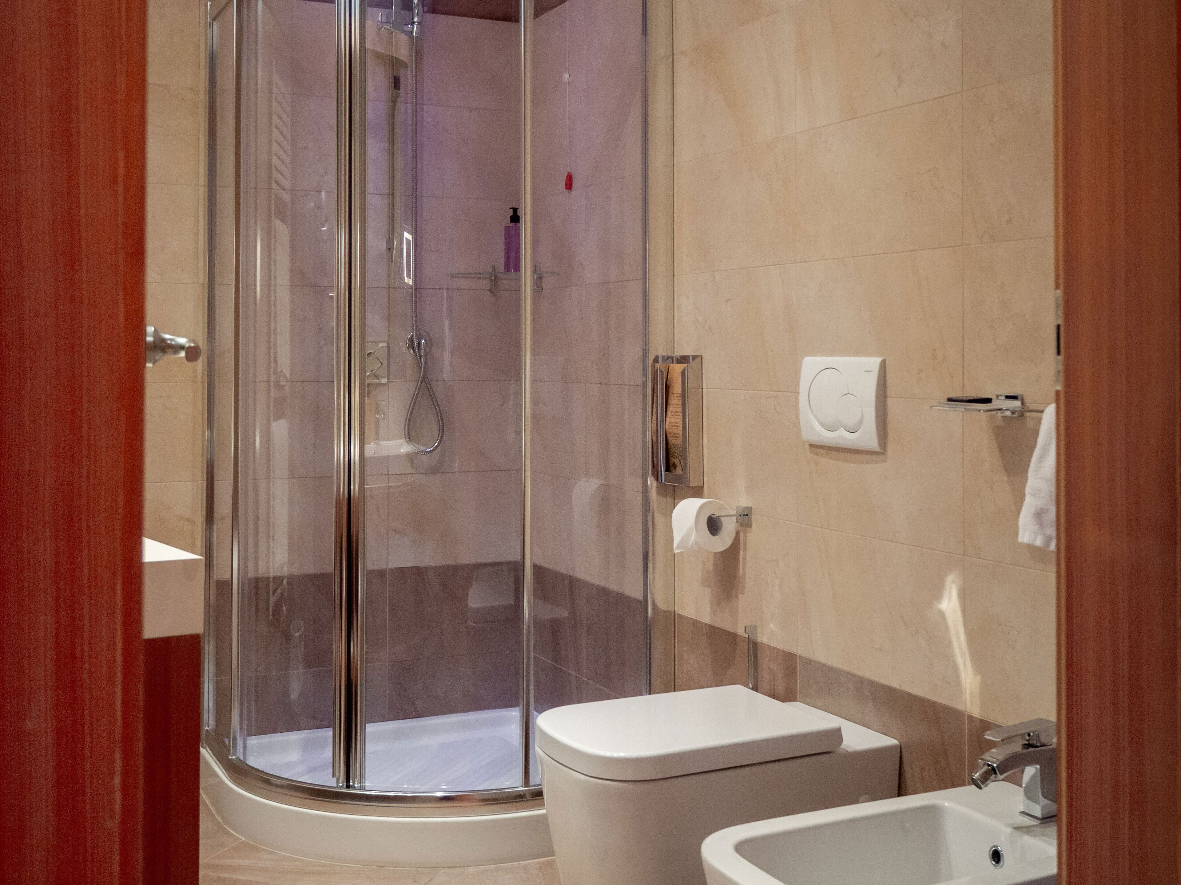 Un baño moderno con cabina de ducha de vidrio, inodoro y lavamanos.