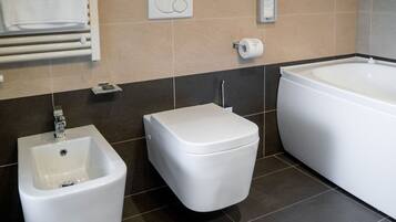 Une salle de bain moderne équipée d’un bidet, de toilettes et d’une baignoire.