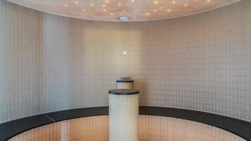 A modern bathroom with a curved design, featuring a central column and a tiled wall with a grid pattern.