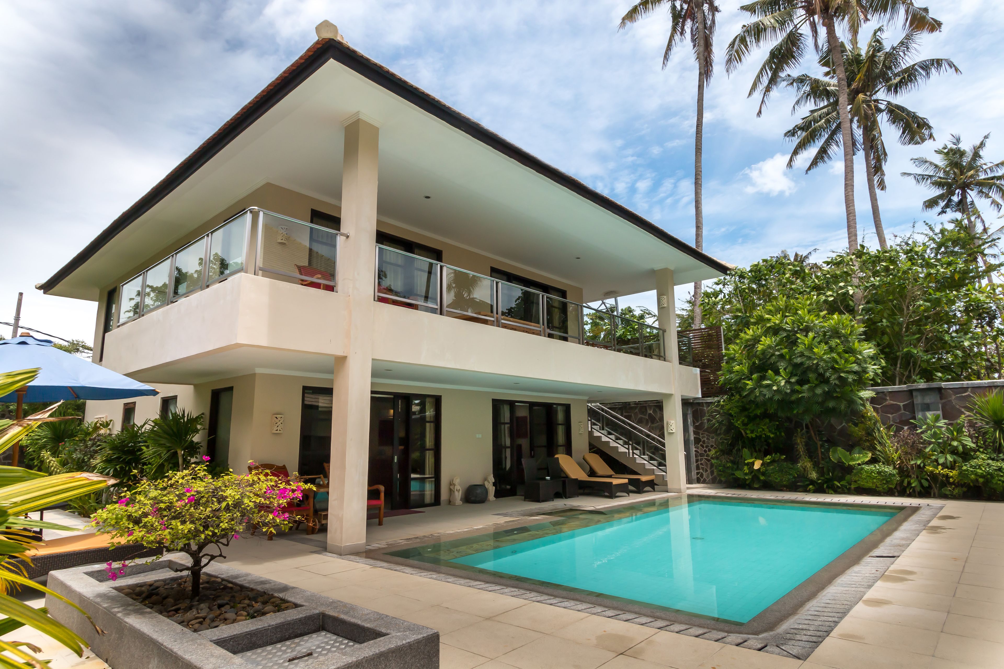 A two-story house with a swimming pool, a balcony, and a staircase leading to the upper floor.