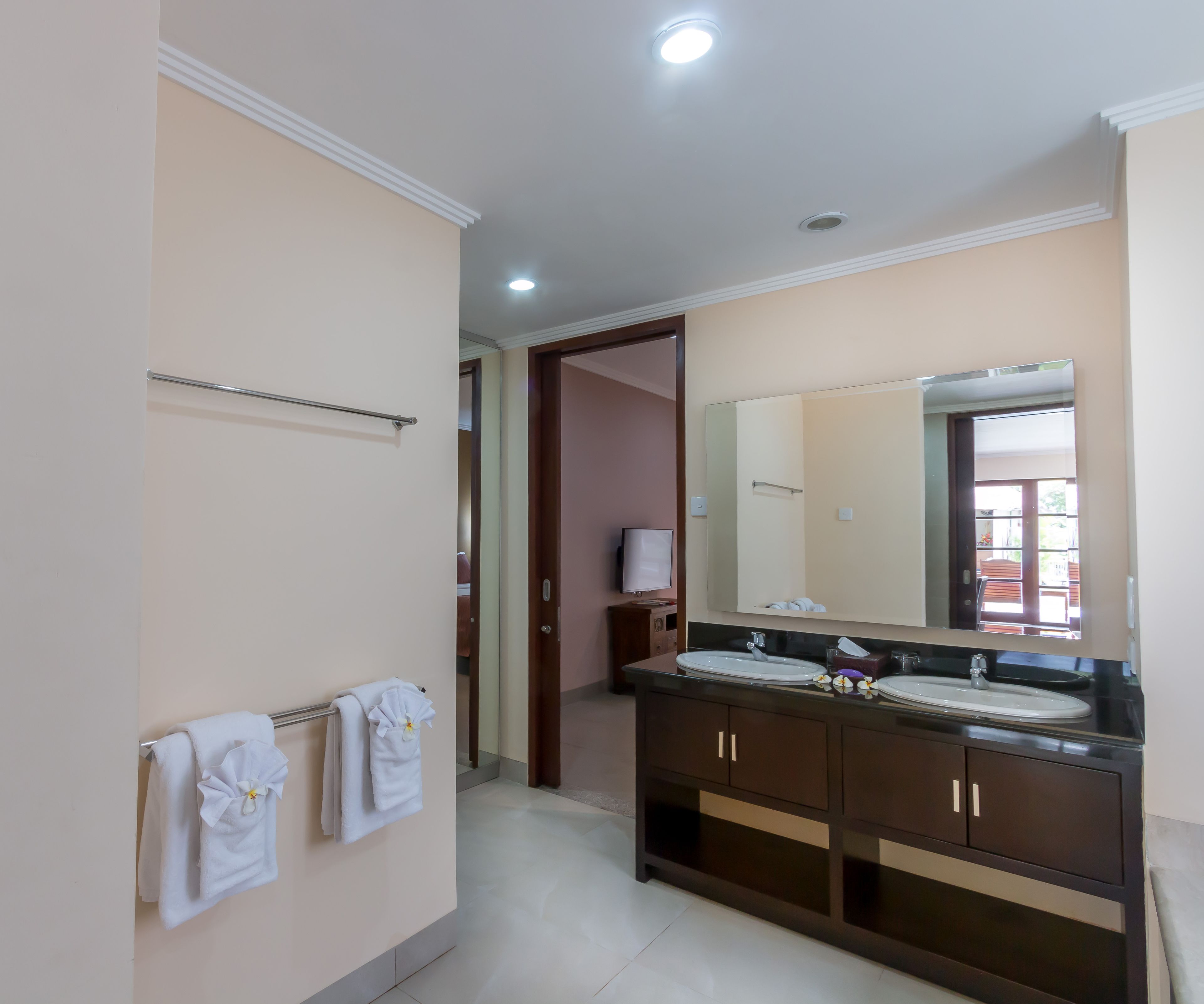 A bathroom with a double sink, a large mirror, and a towel rack with multiple towels.