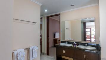A bathroom with a double sink, a large mirror, and a towel rack with multiple towels.