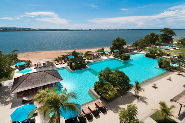 Un complejo turístico con una amplia piscina, acceso a la playa y jardines tropicales.