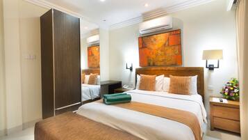 Una habitación de hotel con una cama grande, un armario, una mesita de noche con lámpara y un aire acondicionado instalado en la pared.