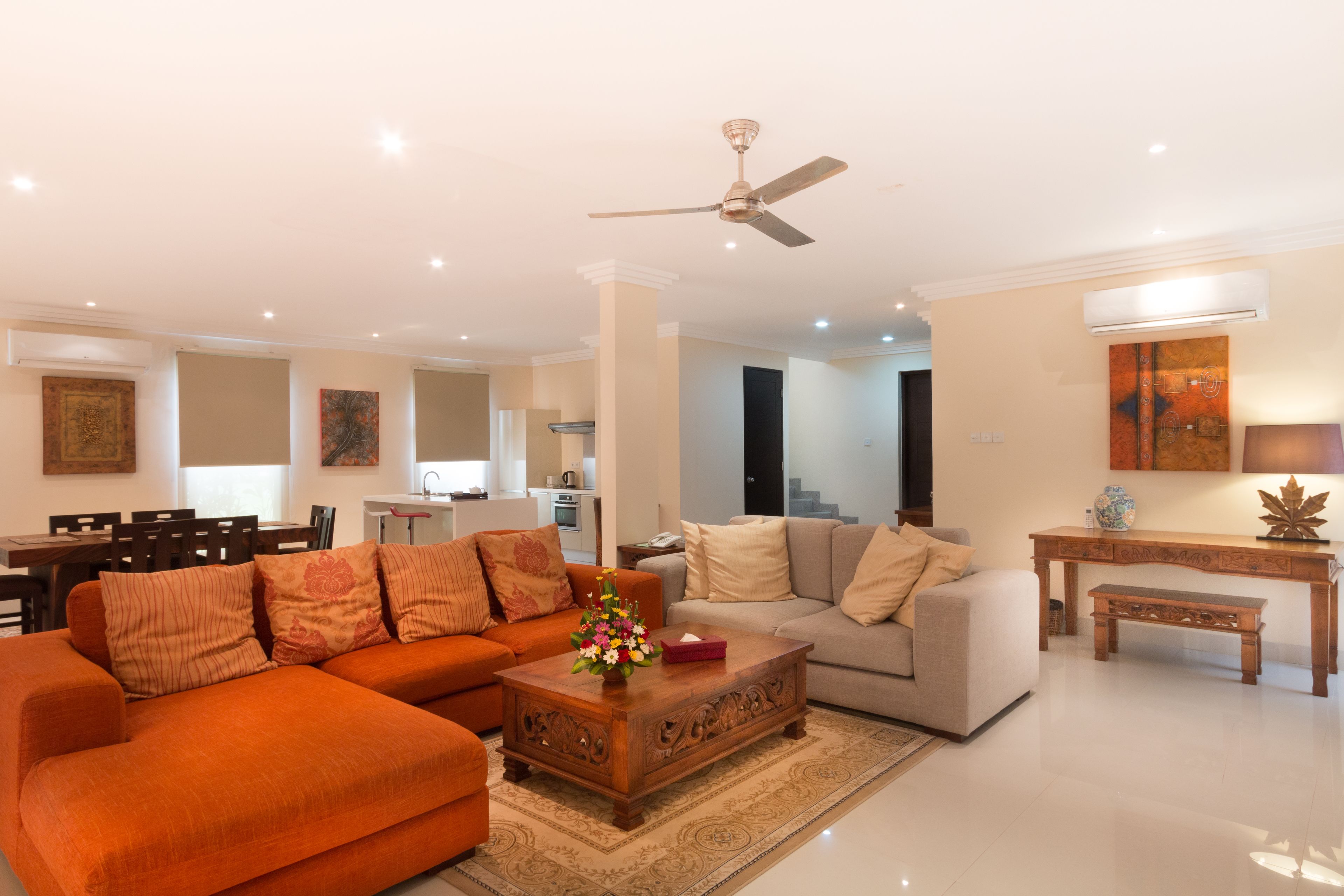 A spacious living room with a sofa, a coffee table, and a dining area in the background.