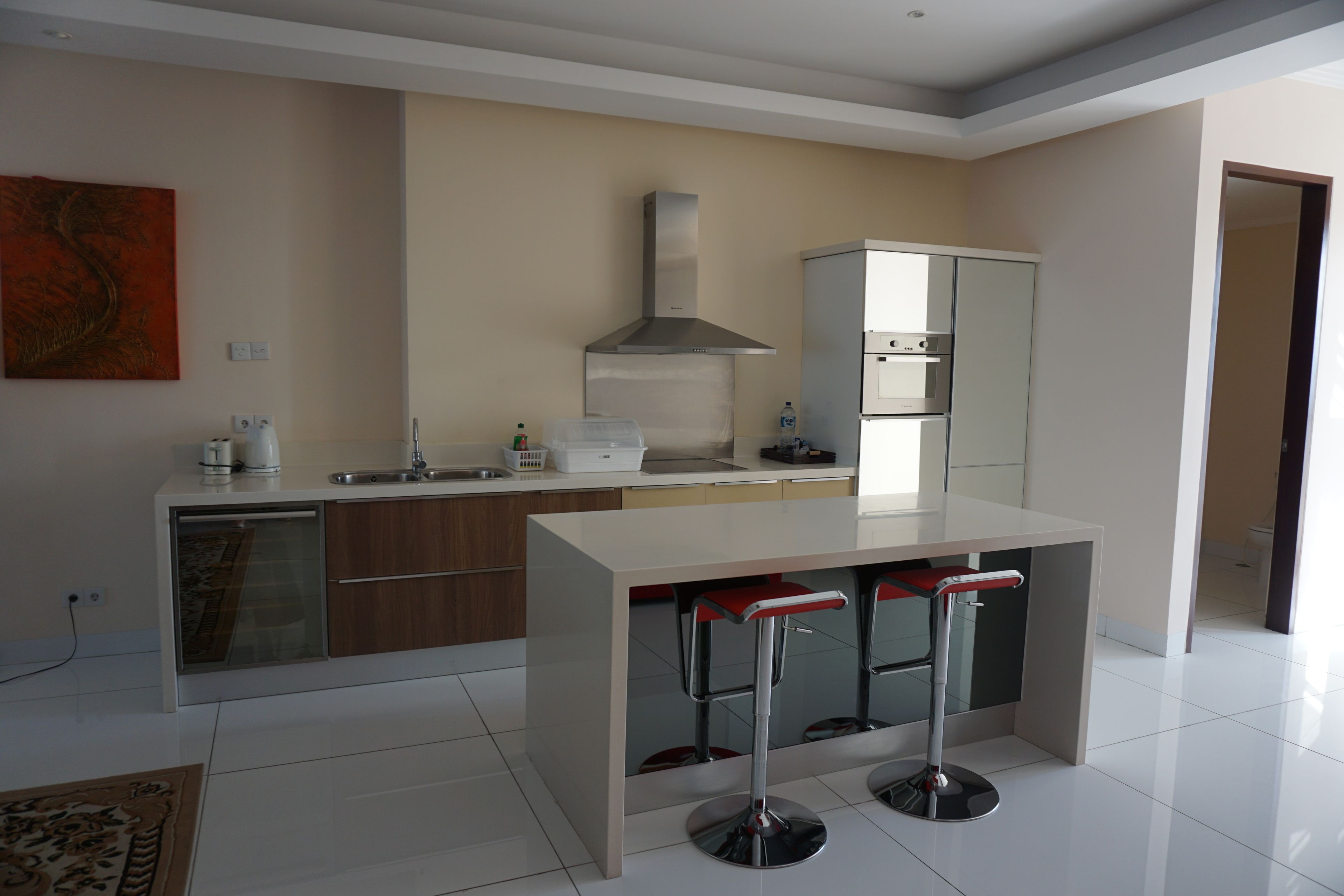 Una cocina moderna con una isla central, taburetes de bar, una campana extractora de acero inoxidable y un horno empotrado.