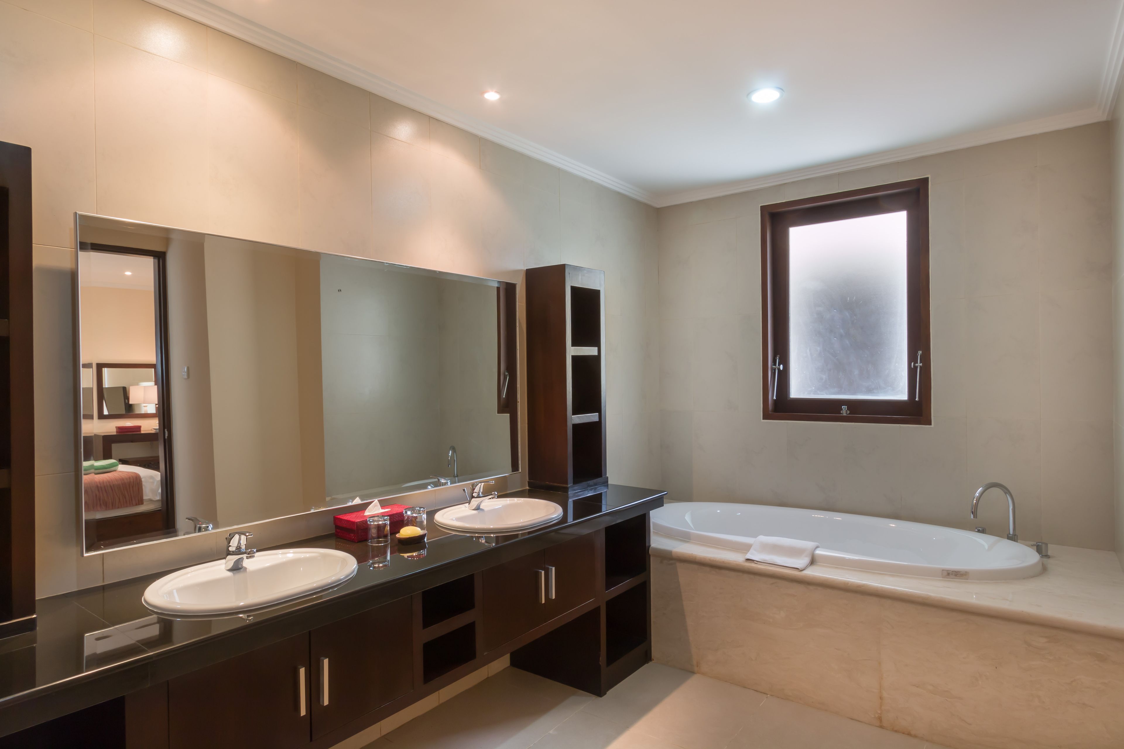 A modern bathroom with two sinks, a large mirror, and a separate bathtub.