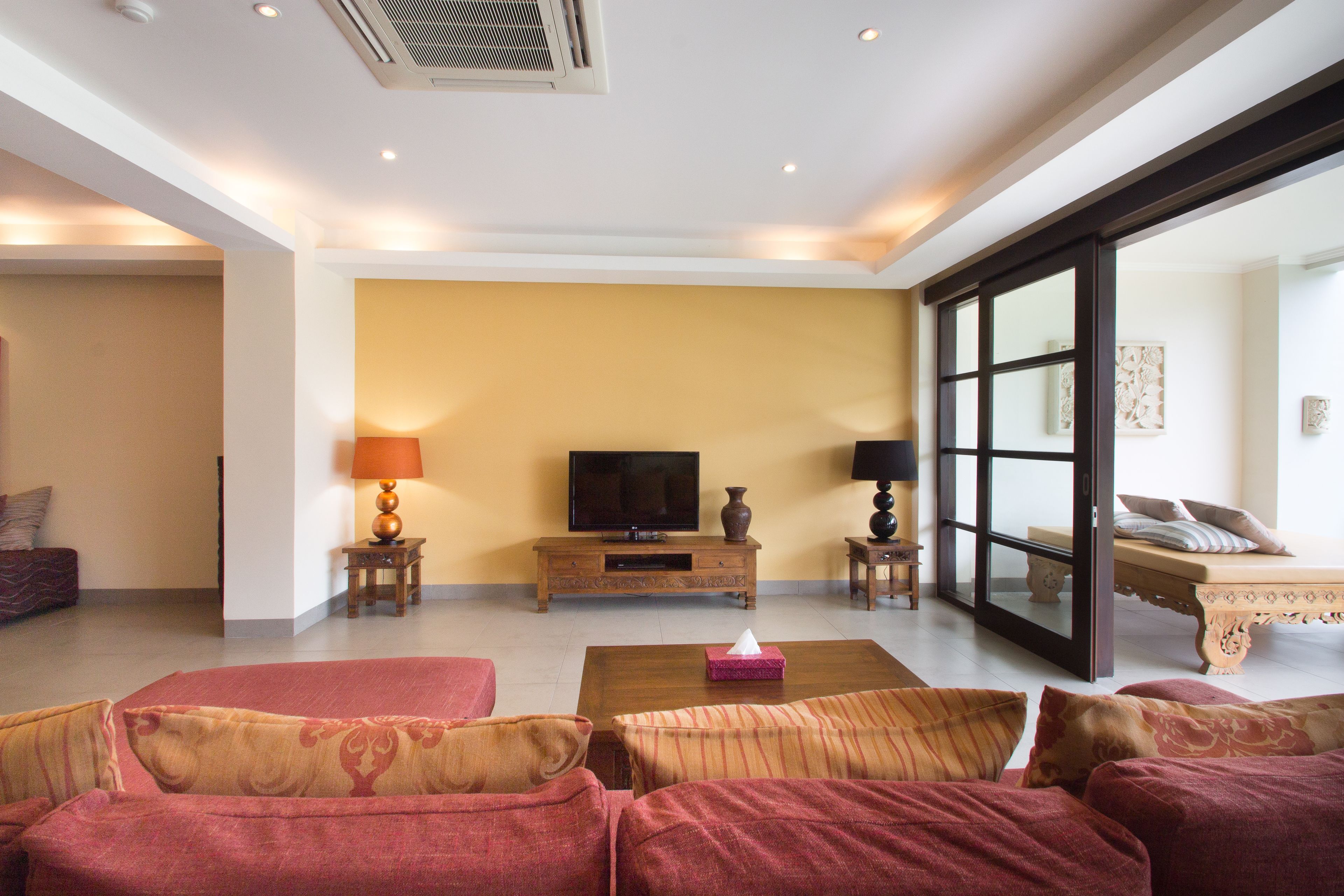A spacious living room with a large sofa set, a television, and a coffee table.