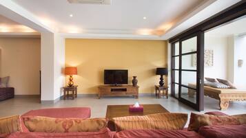 A spacious living room with a large sofa set, a television, and a coffee table.