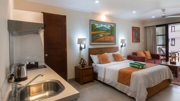 A hotel room with a bed, bedside tables, a desk, a sink, and a painting on the wall.