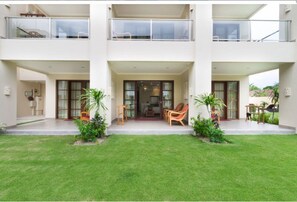 A modern two-story building with a covered entrance, outdoor seating area, and a well-maintained lawn. - Peninsula Bay Resort (Nusa Dua)
