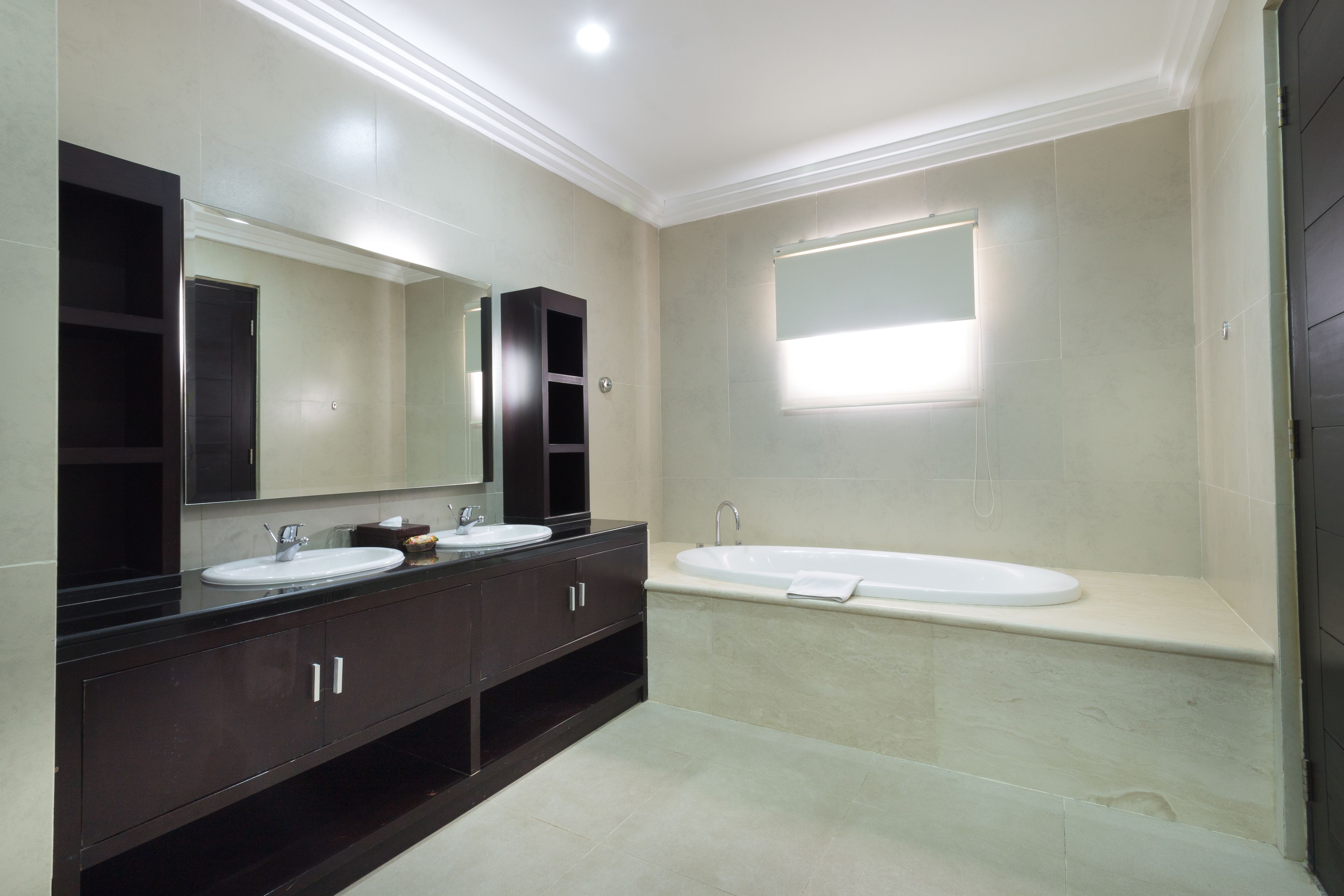 Un baño moderno con dos lavabos, un espejo grande y una bañera.