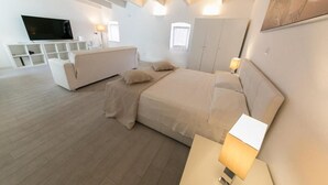 Une chambre à coucher moderne avec un grand lit, une télévision et une commode blanche.