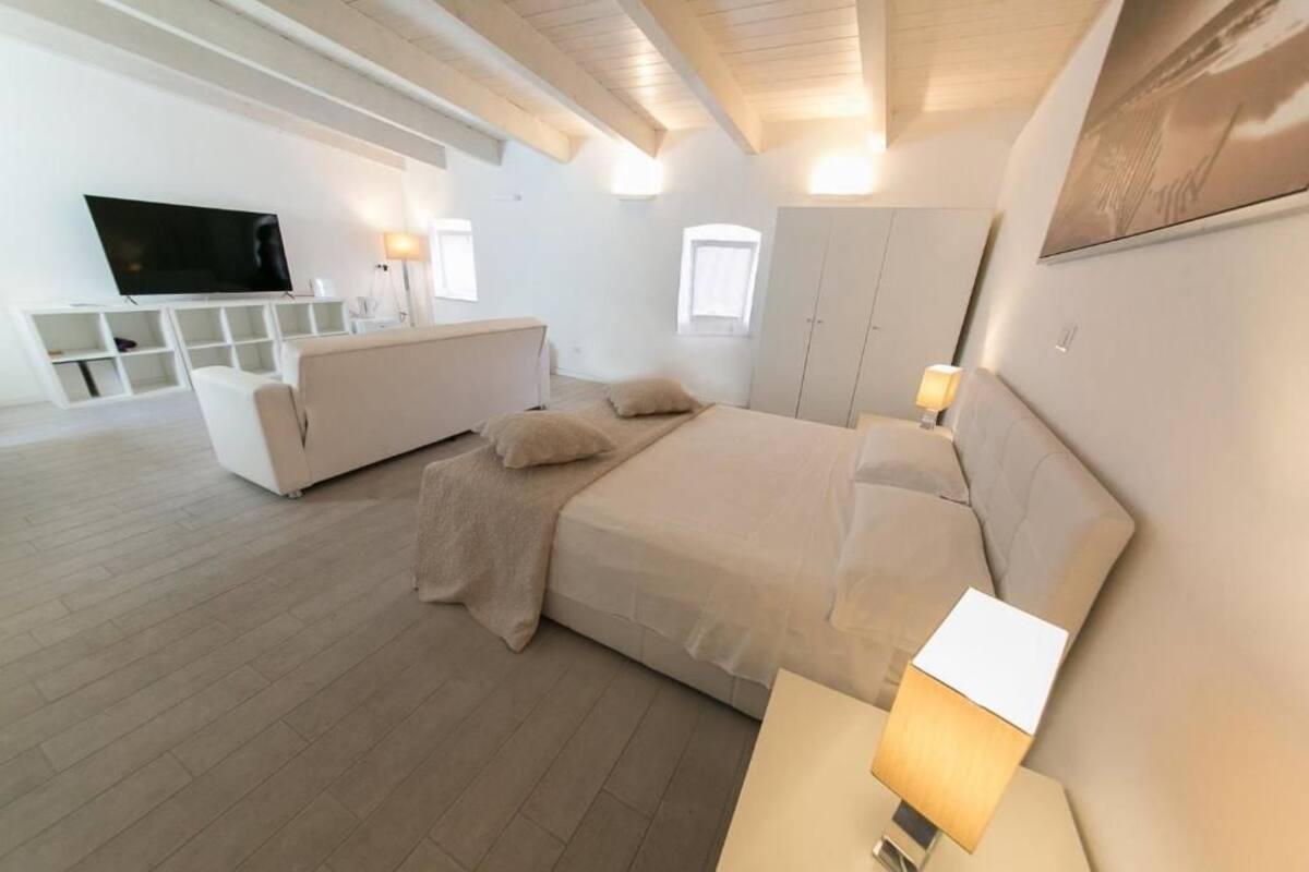 Un dormitorio moderno con una cama grande, un televisor y un aparador blanco.