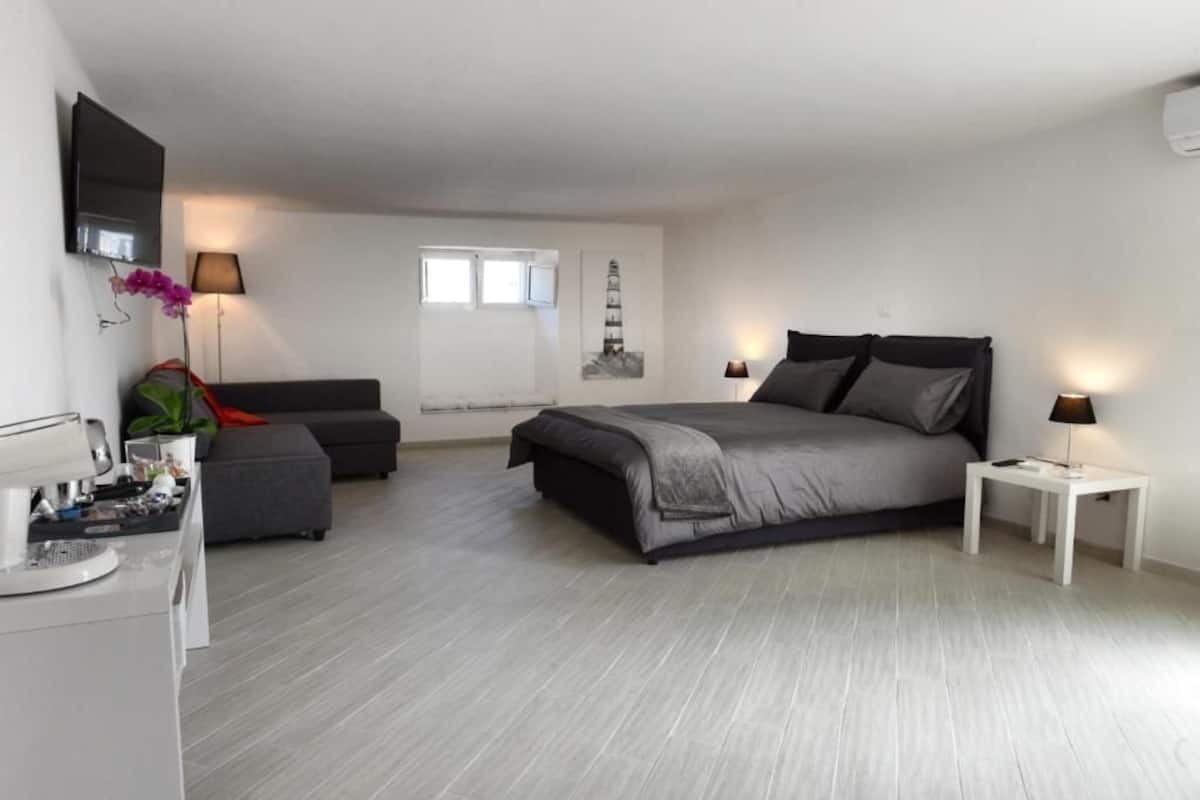 Un dormitorio moderno con cama, escritorio, silla y televisión.
