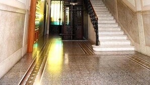 Un vaste hall d’entrée avec un sol en marbre, un escalier et des appliques murales.