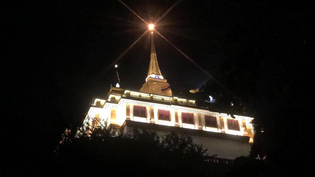 Una vista nocturna de un edificio con una torre destacada y fachada iluminada.