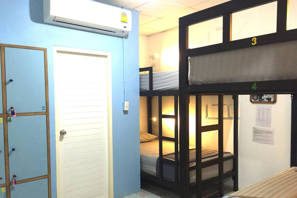 Une chambre de dortoir avec des lits superposés, une porte et un appareil de climatisation.